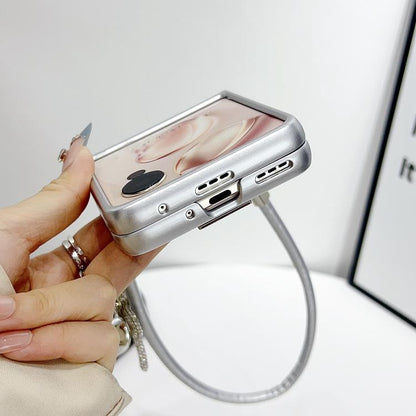 Silver phone case with textured finish and side buttons, with wrist strap attached