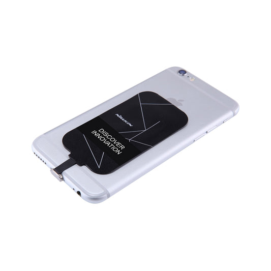 Black wireless charging receiver tag attached on iPhone back with Lightning connector