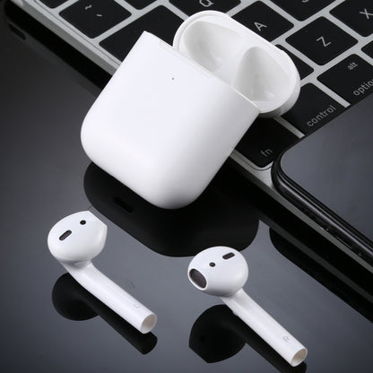 White AirPods-style dummy earbuds and charging case on desk surface