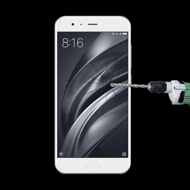 Tempered glass screen protector on smartphone display with impact tool near screen center