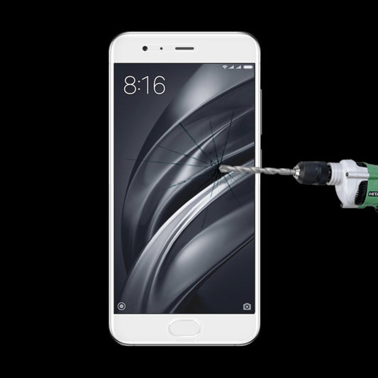 Tempered glass screen protector on smartphone display with impact tool near screen center