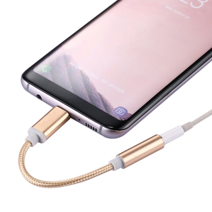 USB-C to 3.5mm audio adapter connected to a smartphone, rose gold metal connectors