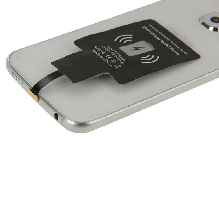 Wireless Qi charging receiver attached to phone back, slim black module