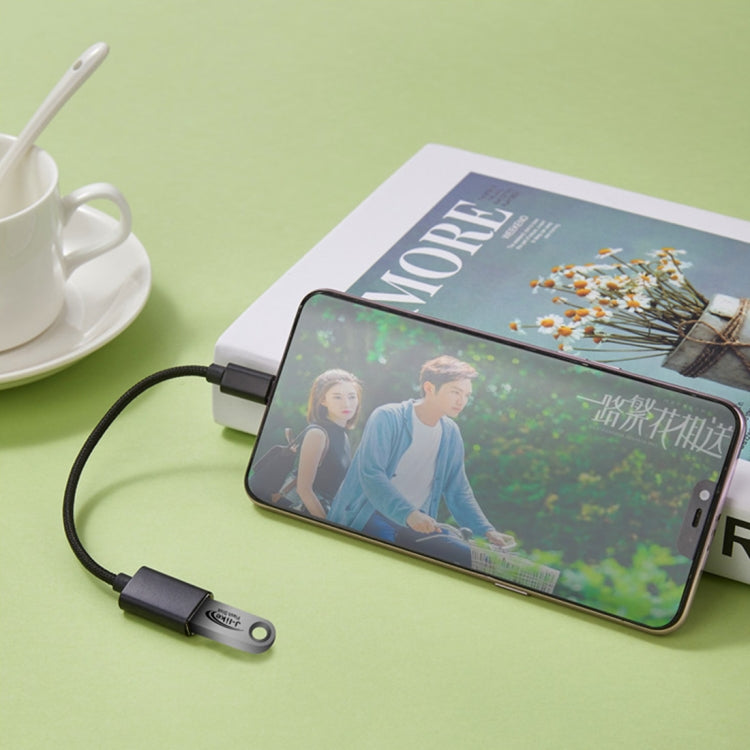 White OTG adapter cable with connector plugged into a smartphone for charging
