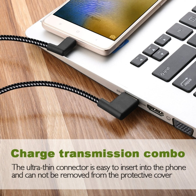 Black braided USB-A to USB-C cable charging phone near laptop ports