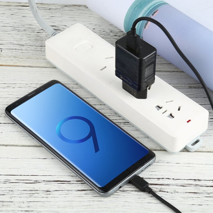 White travel charger with USB ports and USB-C charging cable, shown with phone