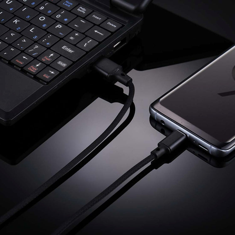 Black USB-A to USB-C cable plugged into laptop and smartphone