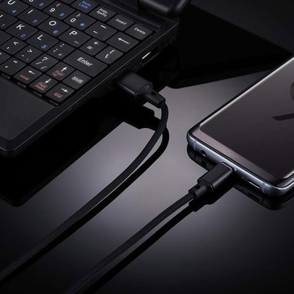 Black USB-A to USB-C cable plugged into laptop and smartphone