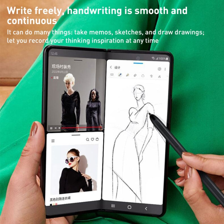 Foldable phone with stylus drawing on screen, held by a hand over green fabric.