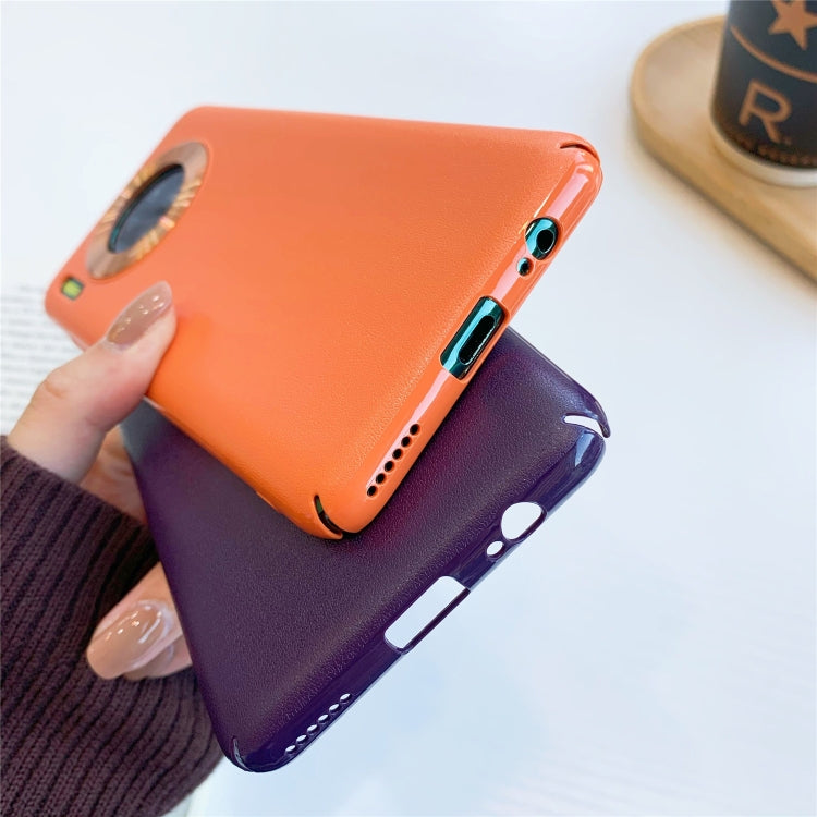 Orange plastic phone case with lens-ring camera protector, shown with a purple case