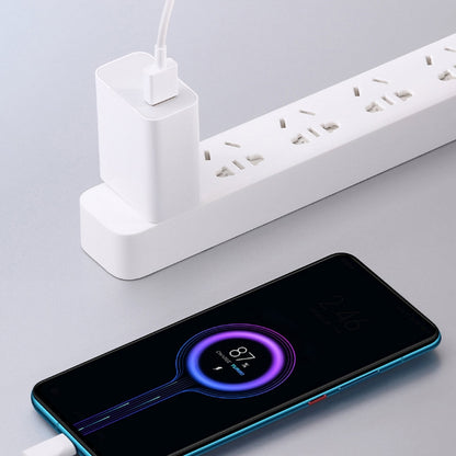 White USB fast charger powering a smartphone from a multi-socket strip