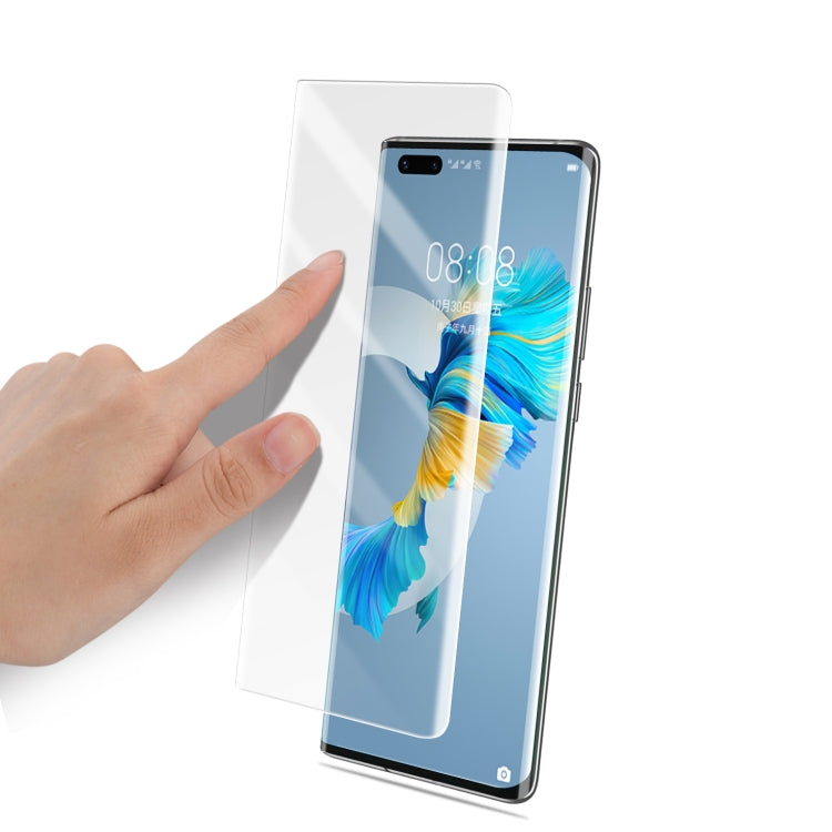 Hand applying clear 3D tempered glass screen protector onto Huawei Mate 40 Pro