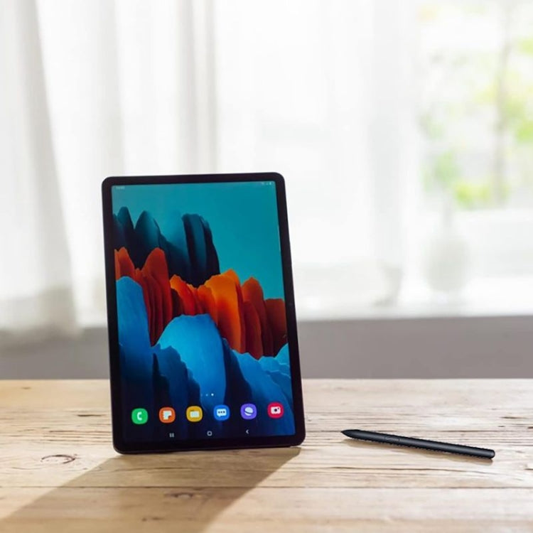 Black stylus lying beside tablet on wooden surface