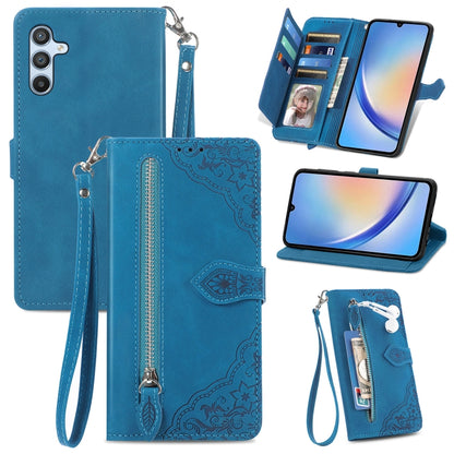 Blue leather phone wallet case with embossed floral design, zipper closure, wrist strap, slots.