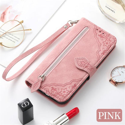 Pink leather phone case with embossed floral pattern, wrist strap, and zipper