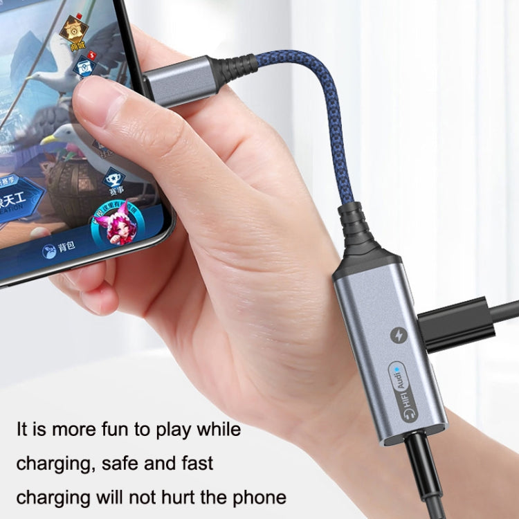 Hand holding USB-C audio and charging adapter cable connected to a phone