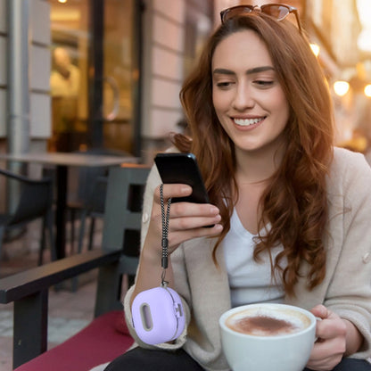 Purple earbuds protective case with carabiner hanging from phone lanyard at cafe