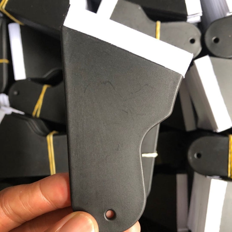 Hand holding a black phone film scraper tool; other scrapers stacked behind