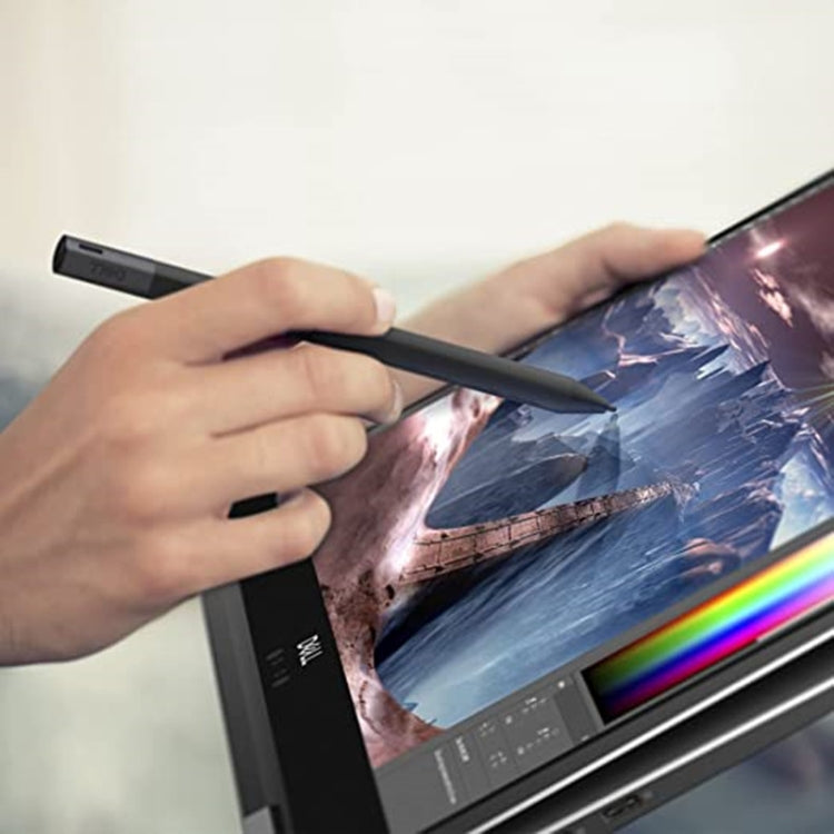 Hands holding a dark stylus pen while writing on a tablet display