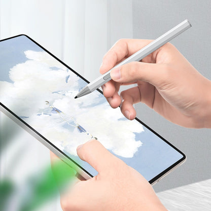 Silver pressure-sensitive stylus pen held above a tablet screen for writing.