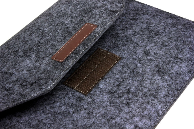 Grey felt sleeve bag detail showing brown leather strap and front flap patch